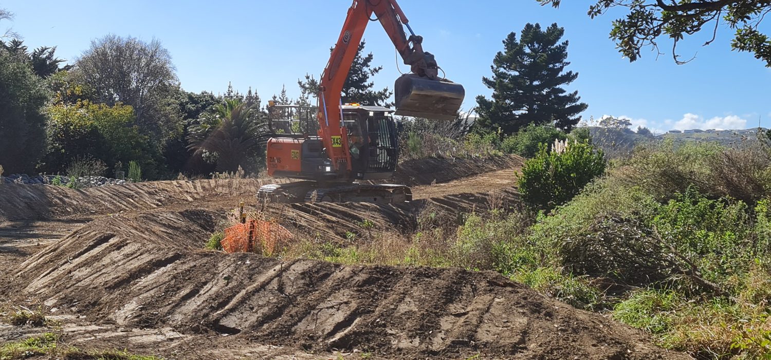 Excavator shaping a drainage channel before it is grassed