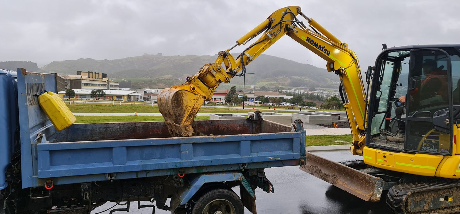 Excavator loading topsoil into a tipper truck