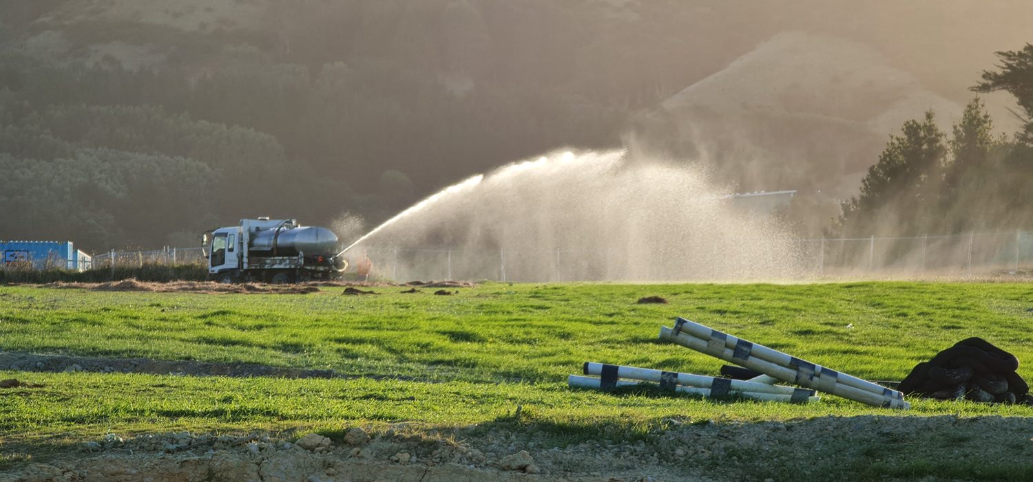 Hydromulch slurry sprayed in a wide arc across a prepared field from a Seed on Earth truck