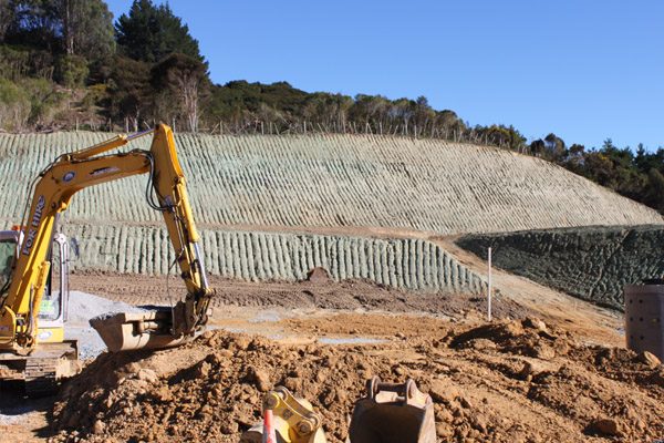 Excavator in front of a freshly hydromulched cut batter