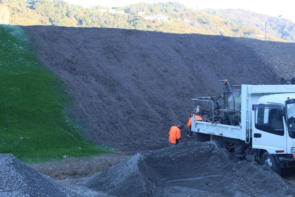 Hydroseeding crew working at the base of a gravel slope