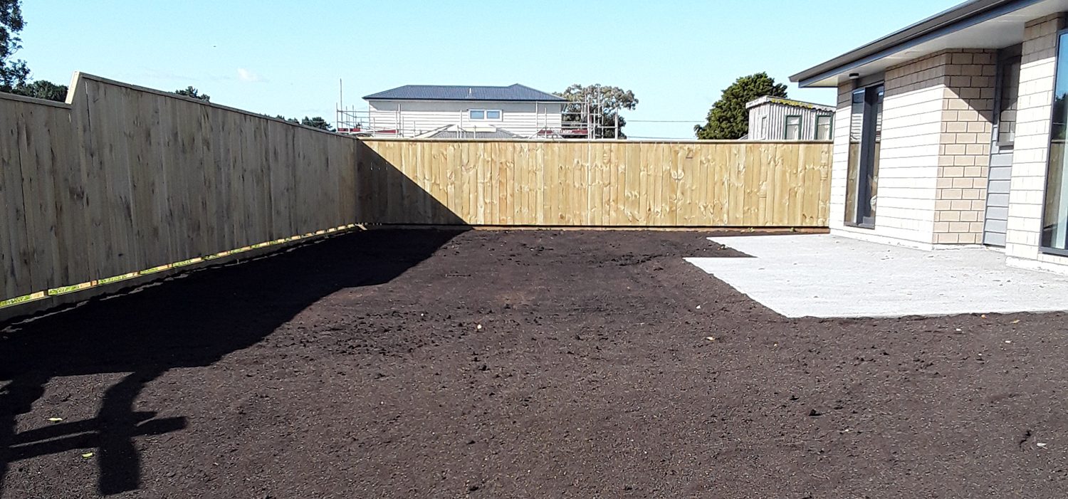 Levelled topsoil prepared for a new lawn behind a new build