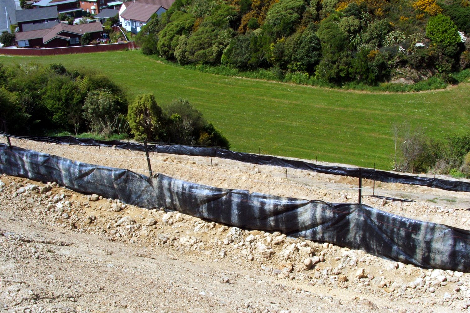 Silt fence at the foot of an earthworks bank with new grass established above