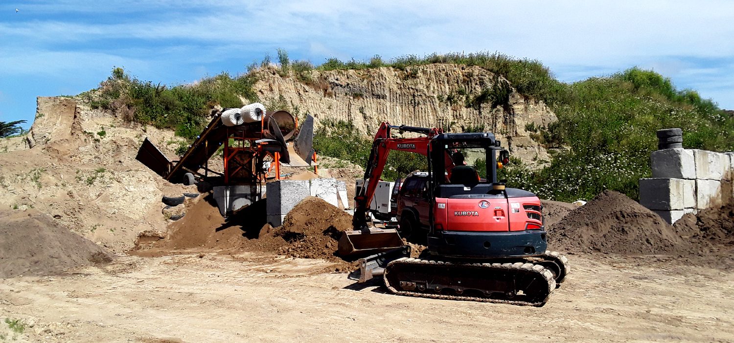 Excavator feeding a screening plant to prepare quality topsoil
