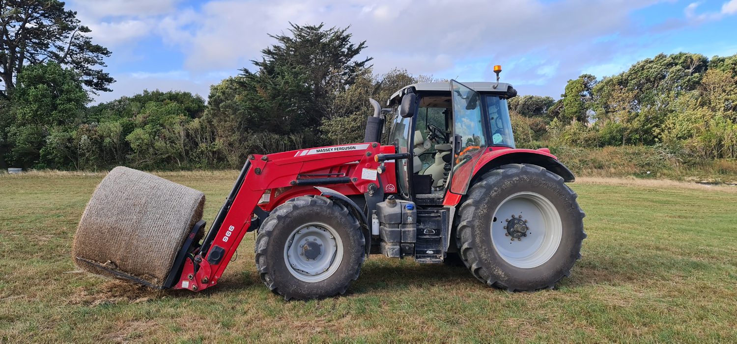 Tractor with front loader working on a grass area