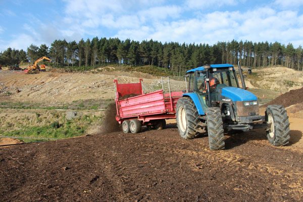 Tractor and trailer spreading topsoil on an earthworks site