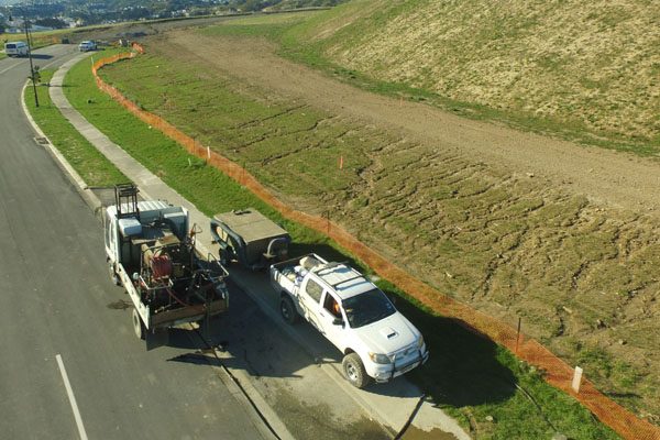 Work vehicles parked beside a grassed road embankment